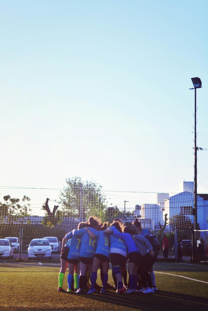 A women's soccer team huddling on the field at sunset in Córdoba, Argentina.